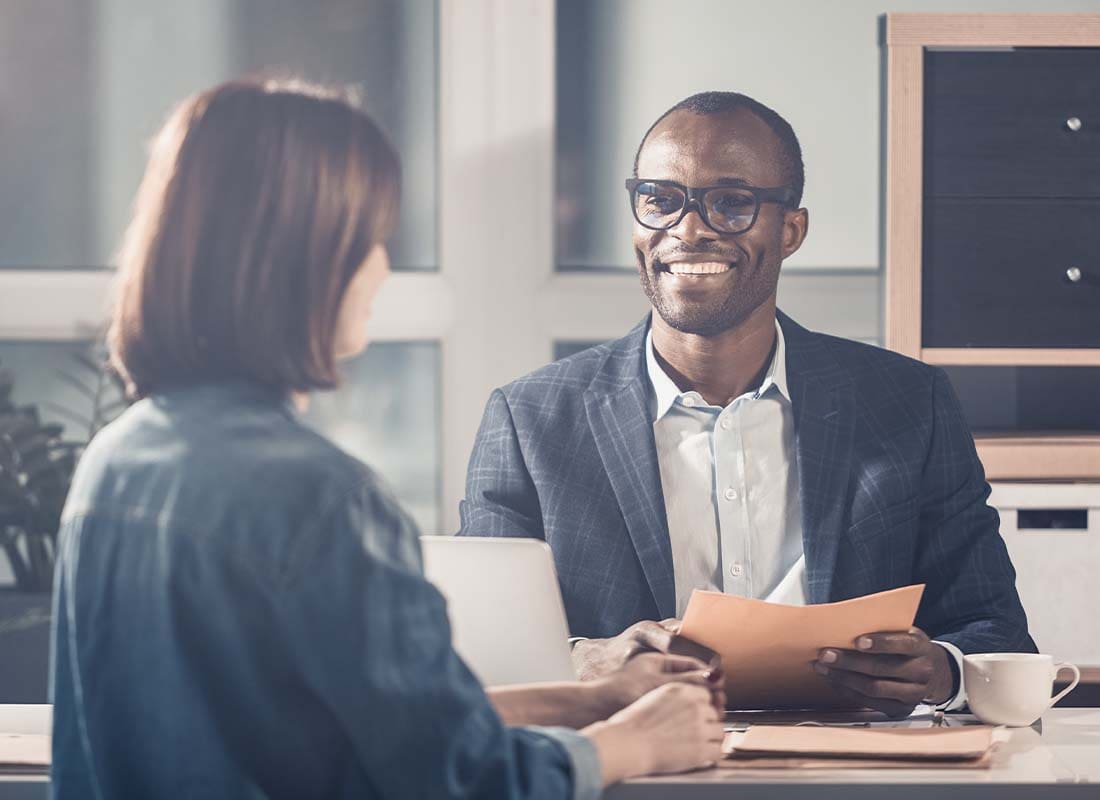 Employment Practice Liability Insurance - Portrait of Smiling Optimistic Manager Looking at His Female Colleague While Sitting at Table and Having a Pleasant Discussion