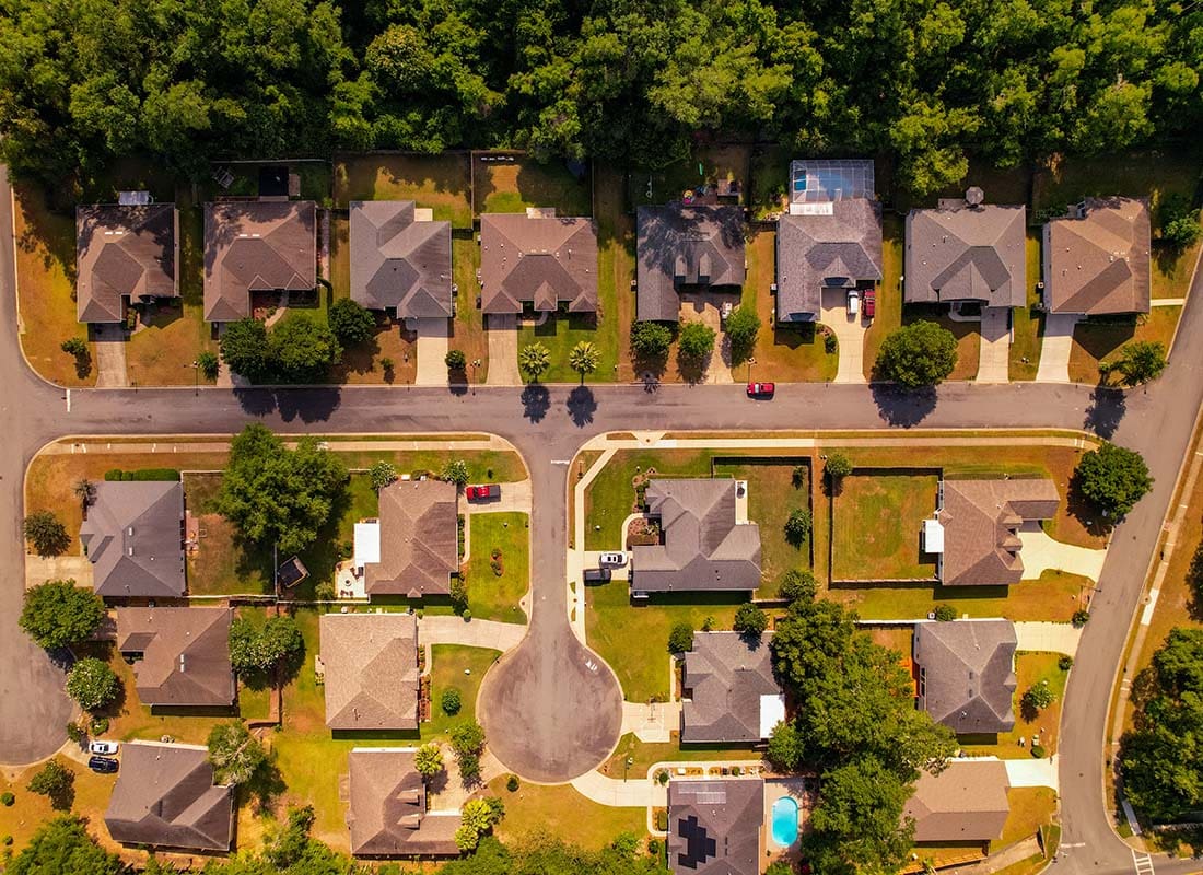Insurance Solutions - Aerial View Looking Down at a Small Residential Neighborhood with Homes Surrounded by Green Foliage on a Sunny Day